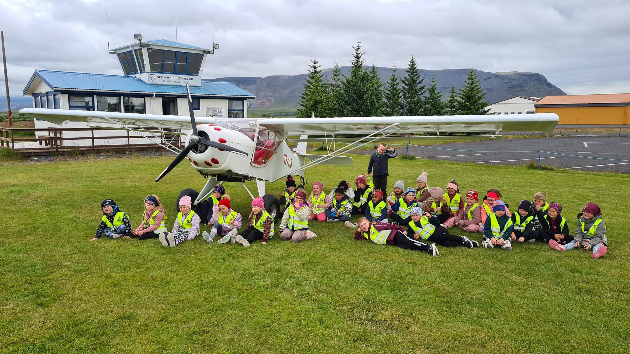 Skólabörn í öryggisvestum við flugvél TF-118 fyrir framan flugturninn á Selfossflugvelli